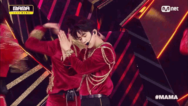 a man in a red velvet outfit is on a stage with a mnet logo in the background