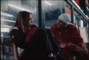 a man and a woman are looking at each other and the man is wearing a supreme jacket