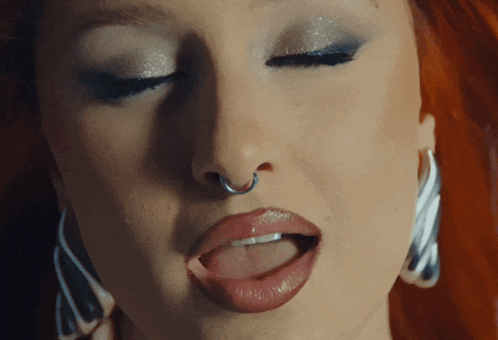 a close up of a woman 's face with a nose ring and earrings