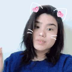 a woman wearing a blue shirt has cat ears on her head