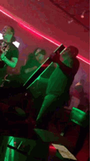 a man is holding a bottle in a dark room with red lights