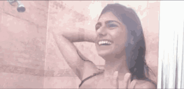 a woman is smiling while taking a shower in a shower stall .