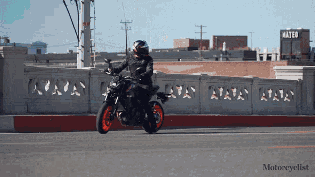 a person riding a motorcycle on a bridge with a sign that says mateu