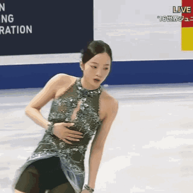 a woman is standing on a ice rink with her hands on her stomach .