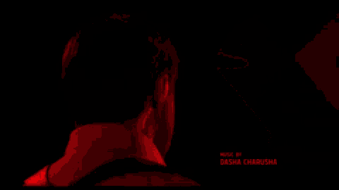 a man in a red shirt is standing in front of a red object that says dasha charusha