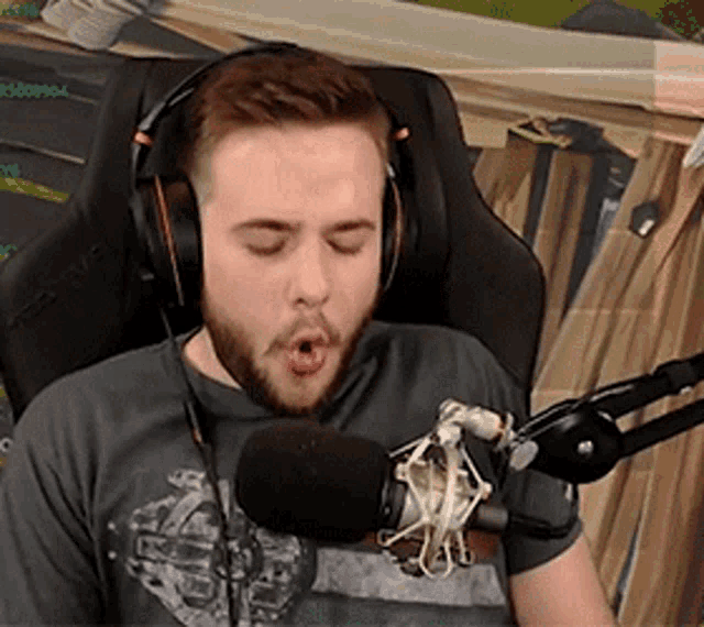 a man wearing headphones is sitting in front of a microphone with his eyes closed .