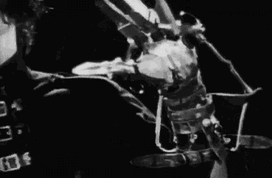 a black and white photo of a man sitting in a chair with scissors in his hands .
