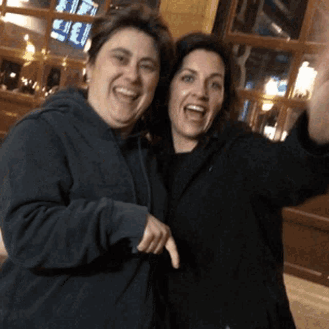 two women are posing for a picture and one of them is pointing at the camera
