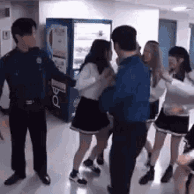 a group of people are dancing in front of a vending machine .