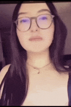 a woman wearing glasses and a necklace looks at the camera .