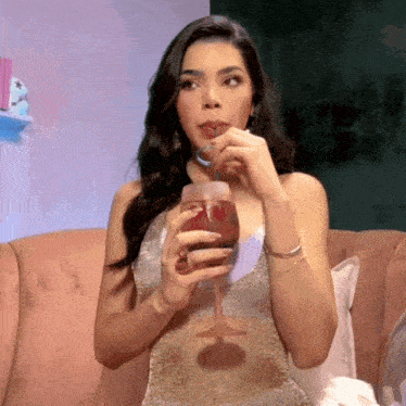a woman is sitting on a couch drinking from a glass