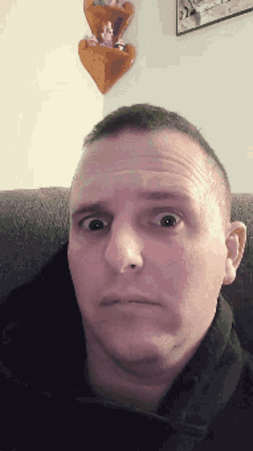 a man sitting on a couch making a surprised face