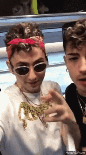 two young men wearing sunglasses and a bandana are posing for a picture .