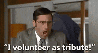 a man in a suit and tie is sitting at a desk and saying `` i volunteer as tribute '' .