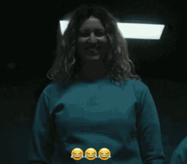 a woman in a blue sweater is laughing with three smiley faces on her chest