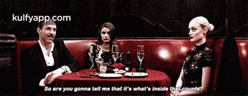 a man and two women are sitting at a table in a restaurant talking to each other