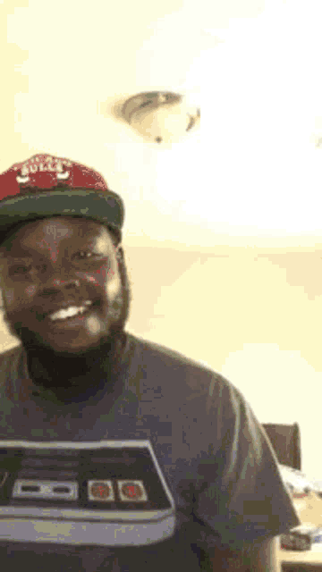 a man with a beard wearing a hat and a t-shirt is smiling .