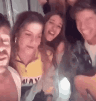 a group of people are posing for a picture together and laughing in a room .