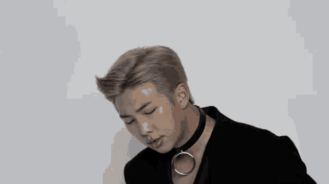 a close up of a man wearing a choker and a black jacket .