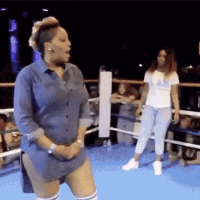 a woman is dancing in a boxing ring while another woman watches .