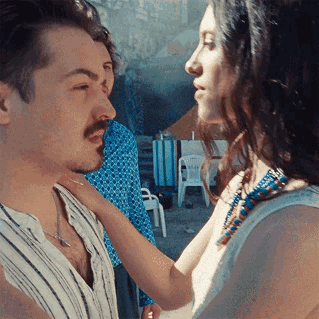 a man and woman are looking at each other and the woman is touching the man 's neck