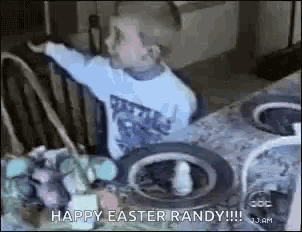 a young boy is sitting at a table with a basket of eggs .