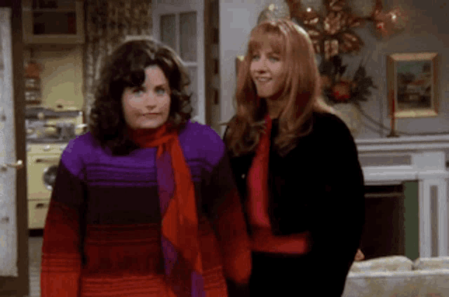 two women stand next to each other in a living room