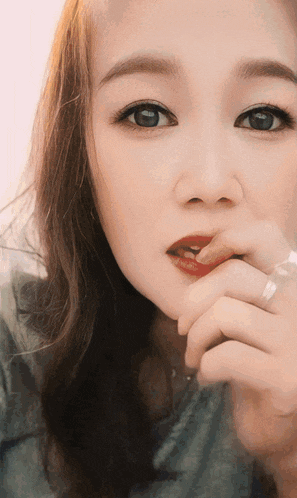 a close up of a woman 's face with a hand on her mouth