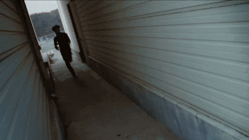 a person walking down a hallway with a white wall behind them