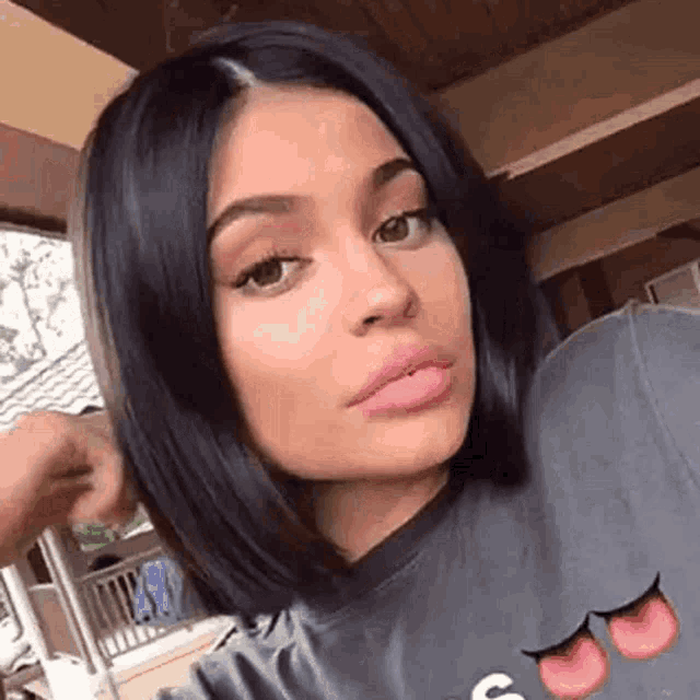 a close up of a woman 's face with short black hair and a t-shirt .