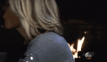 a woman is standing in front of a fireplace with the abc logo visible