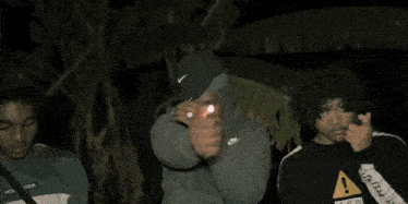 a man in a hat is holding a lighter in his hand .