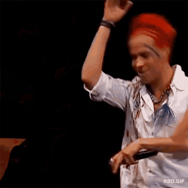 a man with red hair is holding a microphone in his hand and dancing on a stage .