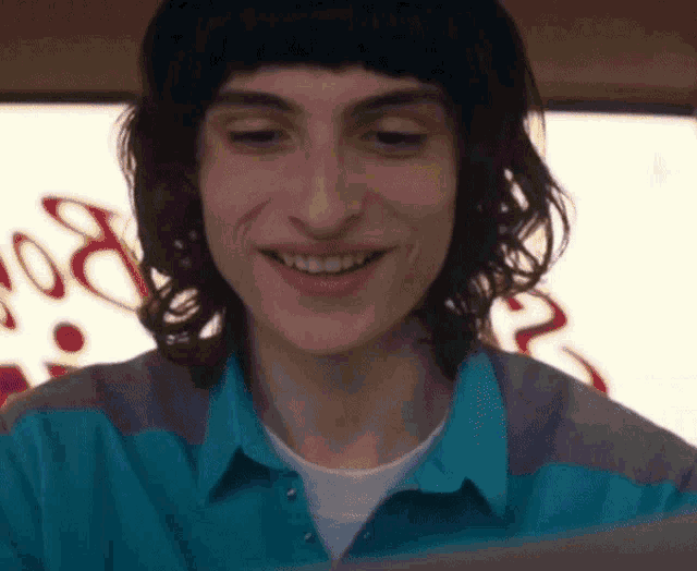 a man in a blue shirt smiles in front of a sign that says ' coca cola '
