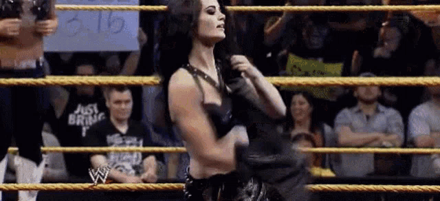 a woman is standing in a wrestling ring with a sign that says ' just bring it ' on it .