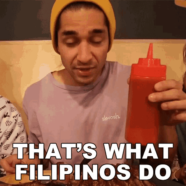 a man holding a bottle of ketchup with the words that 's what filipinos do below him