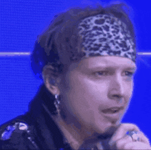a close up of a man wearing a headband and earrings
