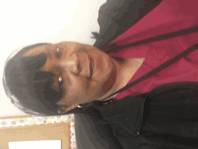 a woman wearing a red scrub top and a black jacket