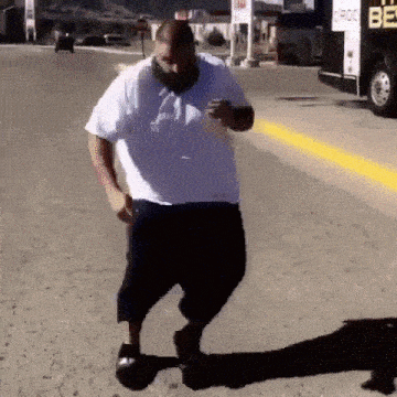 a man in a white shirt is walking down a street while looking at his phone
