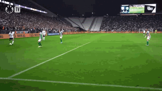 a soccer game is being played in a stadium with a large tv screen in the background