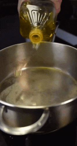a bottle of oil is poured into a pot of water