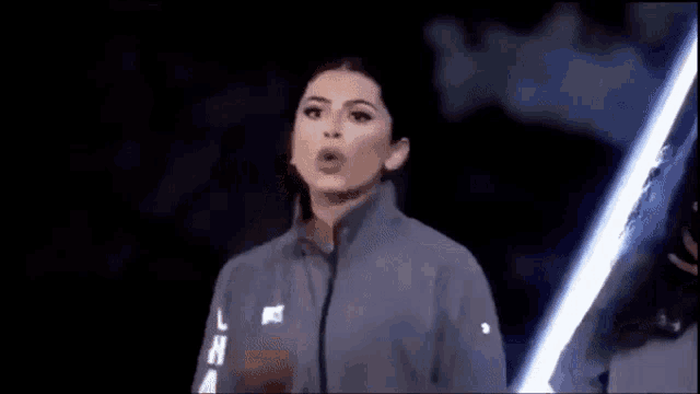 a woman is blowing a kiss while holding a light saber in the dark .
