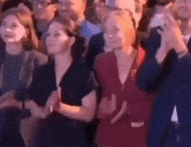 a group of people are sitting in a crowd and applauding at a concert .
