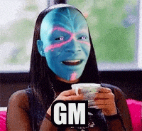 a woman with a blue face painted on her face is holding a cup of tea .