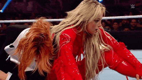two women are wrestling in a wrestling ring and one of them is wearing a red outfit .