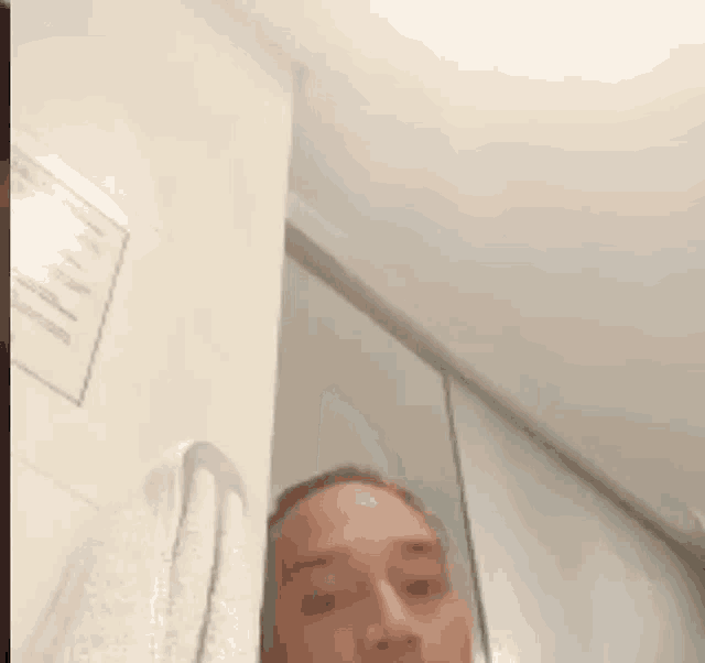 a man is taking a selfie in a bathroom with a towel hanging from the wall .