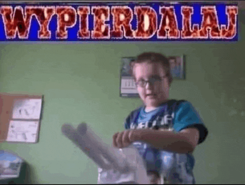 a young boy is standing in front of a sign that says wypierdalaj