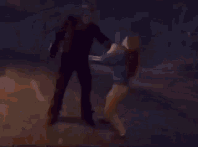 a man is standing next to another man in a dark room .