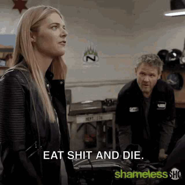 a woman stands next to a man in a garage with the words eat shit and die above her