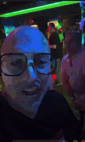 a man wearing glasses is standing in front of a crowd